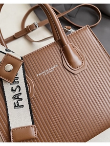 Detail of brown embossed leather tote with a wide fashion strap and vertical textures