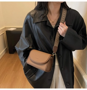 Sac bandoulière marron texturé avec large sangle tissée géométrique sur l'épaule du modèle