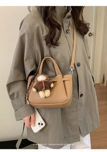 Détail du sac seau kaki en cuir grainé avec un pendentif ours mignon et bandoulière