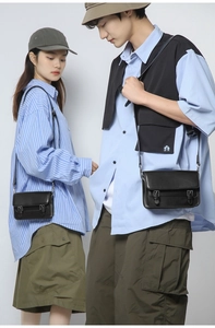 Detail of vintage black messenger bags with double buckle straps on models