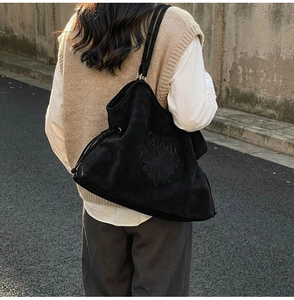 Detail of a large black suede tote bag with flower and Malodi letter embroidery