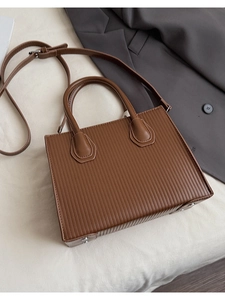Detail of dark brown rectangle crossbody bag with vertical stripe embossed texture