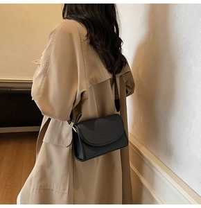 Détail du sac bandoulière noir texturé avec large sangle à motifs sur trench