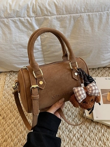 Brown leather Boston bag with gold hardware and a cute puppy charm shown in lifestyle setting