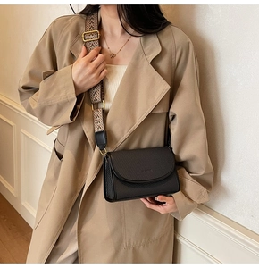 Détail d'un sac bandoulière tissé noir avec une large bandoulière jacquard géométrique