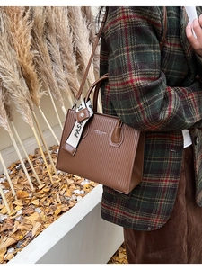 Brown textured leather tote bag with elegant silk ribbon detail and gold lettering