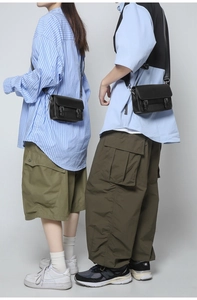 Detail of black tactical crossbody bag with double buckles and canvas shoulder strap