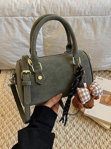 Dark green Boston bowling bag with leather handles and a plush bear keychain charm