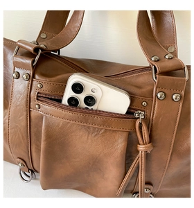 Detail shot of the vintage brown leather bag featuring an external pocket and metal rivets