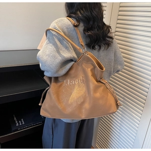 Detail of caramel suede leather tote bag with daisy embroidery and drawstring closure