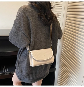 Détail du sac bandoulière crème avec texture tissée et large sangle en tissu à motifs