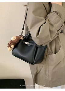 Détail du sac seau noir en cuir grainé avec fermoir rotatif et charm singe amovible