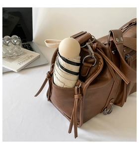 Detail view of large leather pillow bag side pocket holding a folding umbrella