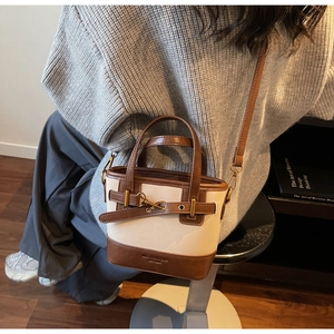 Detail of a chic beige canvas and brown leather crossbody bag shown in a lifestyle setting