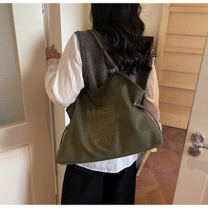 Olive green suede tote bag with letter embroidery and drawstring detail on model