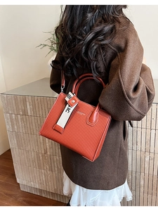 Detail of burnt orange shoulder bag with vertical embossed leather and chic decorative strap
