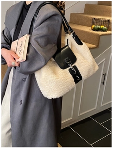 Side view of cream-white plush tote bag with black leather strap and metal clasp detail