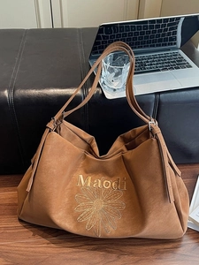 Brown faux suede tote bag with yellow daisy embroidery in a stylish office setting