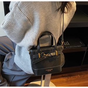 Detail of a black vintage bucket bag with gold hardware shown in a lifestyle scene