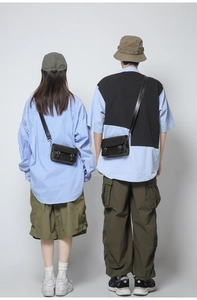 Rear view of two models wearing black leather crossbody bags with vintage buckle details