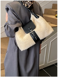 Detail of white plush shoulder bag with black leather trim and silver chain on a coat