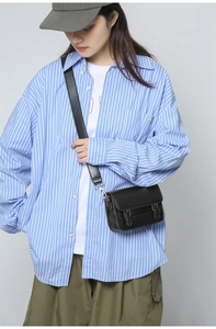 Detail of a black leather crossbody bag with silver buckles and a casual urban style