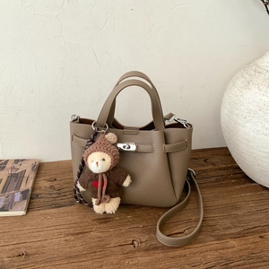 Détail du sac seau en cuir taupe avec poignées et un pendentif ours en peluche