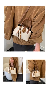 Detail of a retro shell bag with cream leather, contrast handle, and beaded tassel