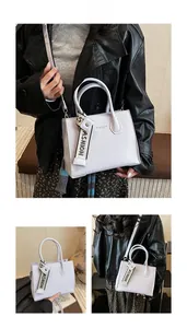 Detail view of purple handbag featuring vertical embossed stripes and fashion pendant