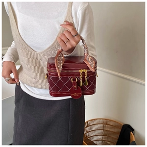 Close-up of wine red box bag with quilted diamond patterns and silk scarf handle detail