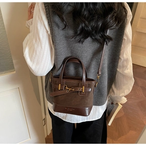 Detail of vintage dark brown bucket bag with mixed textures and gold hardware
