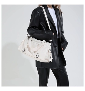 Model shot of cream white Boston bag with motorcycle style rivets and long fringe tassels