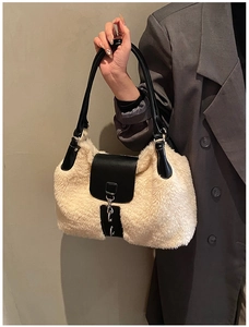Detail of plush winter handbag featuring cream faux fur with black leather trim and metal chain