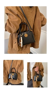 Detail of black semi-circular shell bag with gold round lock and beaded charm accessory