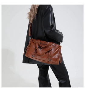 Detailed side view of vintage brown leather tote bag with metallic ring and long strap