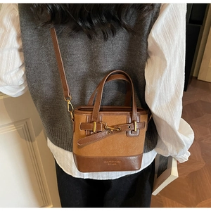 Detail view of brown vintage bucket bag with leather splicing and gold metal buckle