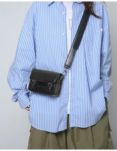 Detail of black crossbody square bag with silver hardware on a casual outfit