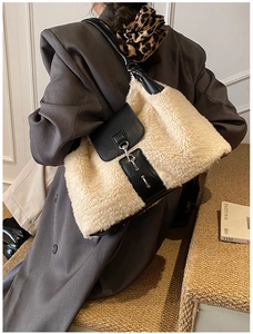 Detail of plush beige faux fur shoulder bag with black leather flap and metal chain lock