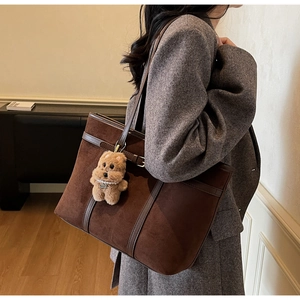 Brown vintage suede tote bag with bear charm detail worn on shoulder with grey coat