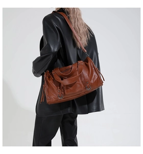 Detailed view of the caramel PU leather pillow bag texture and stylish metal zipper pockets