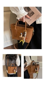 Detail of brown leather tote bag with gold lettering and cute teddy bear charm accessory