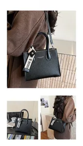 Detail of black pleated crossbody bag with silk scarf handle and leather strap