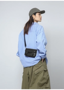 Crossbody black camera bag style phone purse shown on model with casual striped shirt