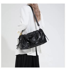Detail of black faux leather Boston bag with silver D-rings and long fringe zippers