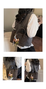 Detail of dark brown tote bag with bear charm, gold logo and adjustable strap