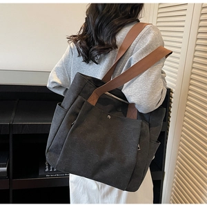 Détail du sac cabas en toile grise avec poche avant et bandoulière en nylon marron
