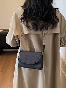 Petit sac carré noir avec bandoulière ethnique porté sur un trench-coat beige élégant