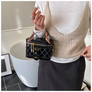 Detail of black quilted box bag featuring contrast stitching and silk scarf handle