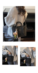 Detail of black crossbody tote bag with gold lettering and cute bear plush charm
