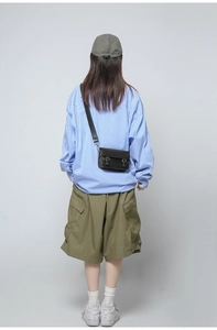 Detailed back view of a black crossbody bag with double buckle straps on a model